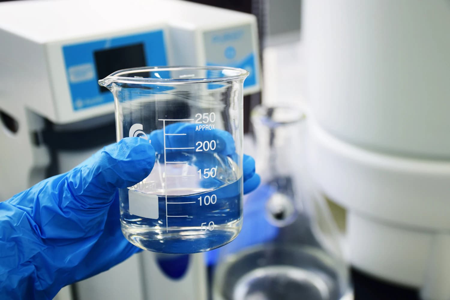 Chemist holding a beaker of cleaning solution during batch quality control