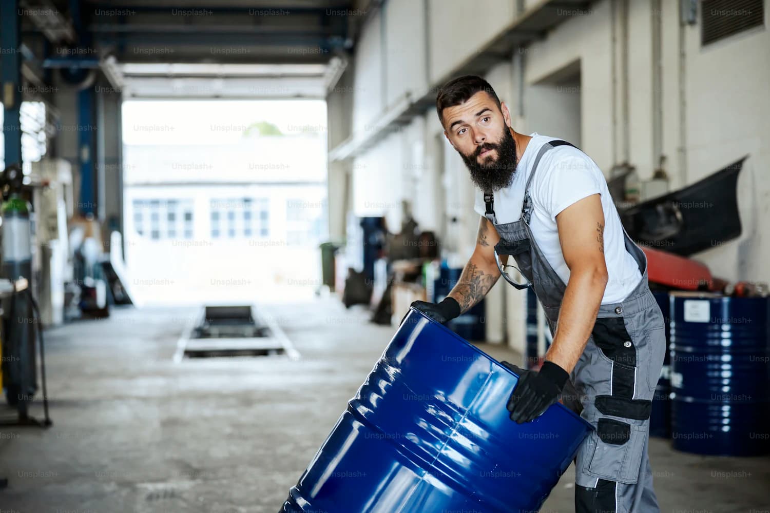 Worker moving chemical drums in a plant