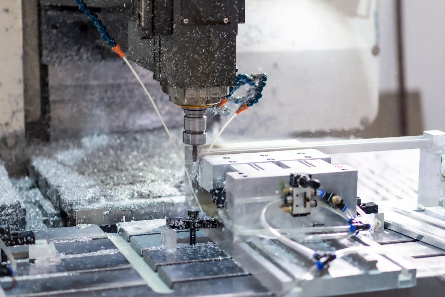 CNC machining centre flooding a steel part with coolant during cutting